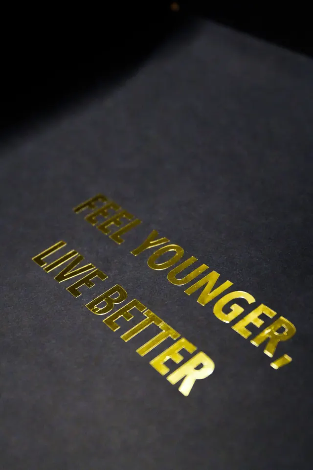 Feel younger, live better printed in gold on black paper