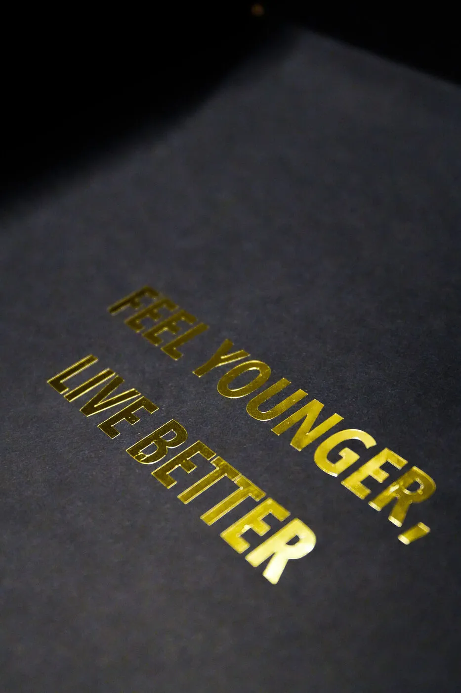 Feel younger, live better printed in gold on black paper