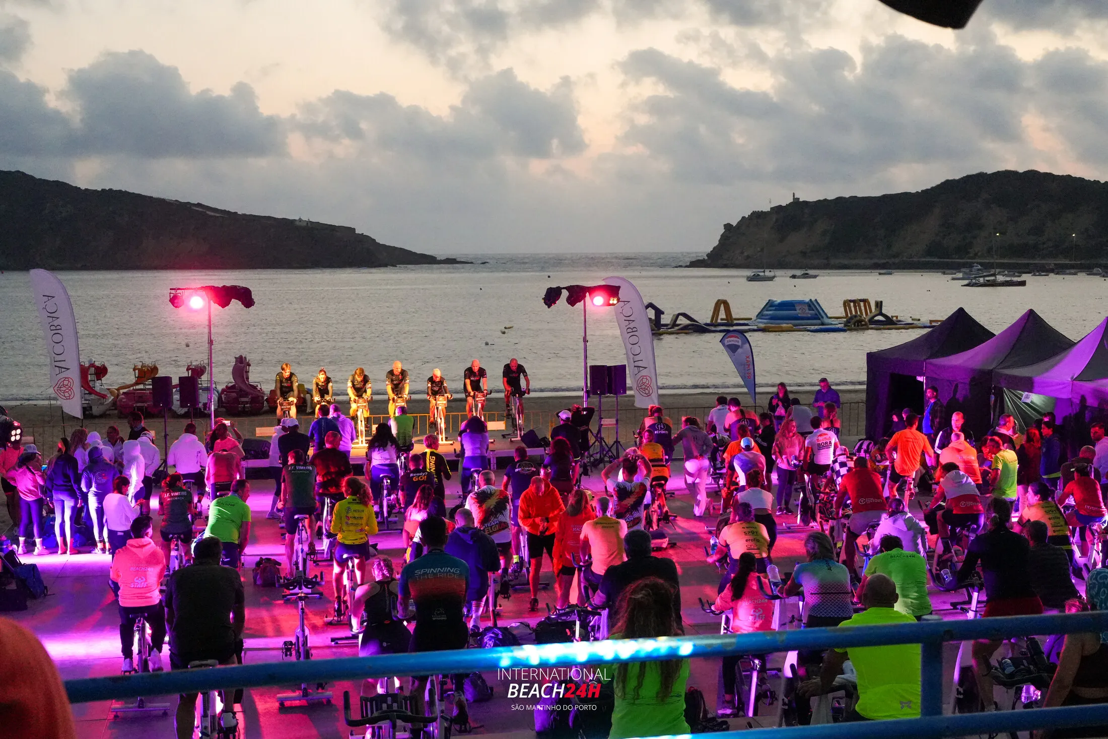 Participants, illuminated stage and São Martinho do Porto bay at dusk